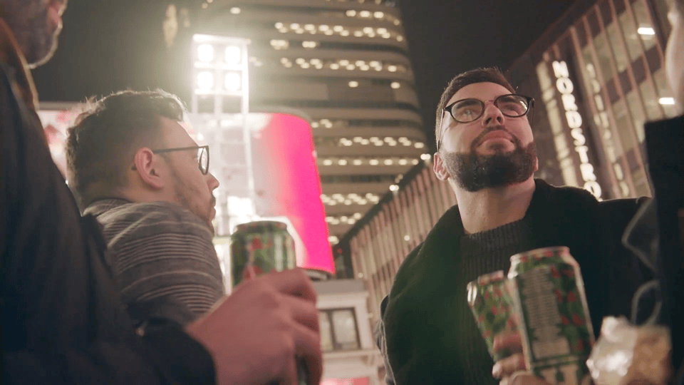 Animated gif of a group of four adult friends drinking Heineken tall cans transitioning to a Heinken holidays branded billboard with their group photo in Yonge Dundas square.